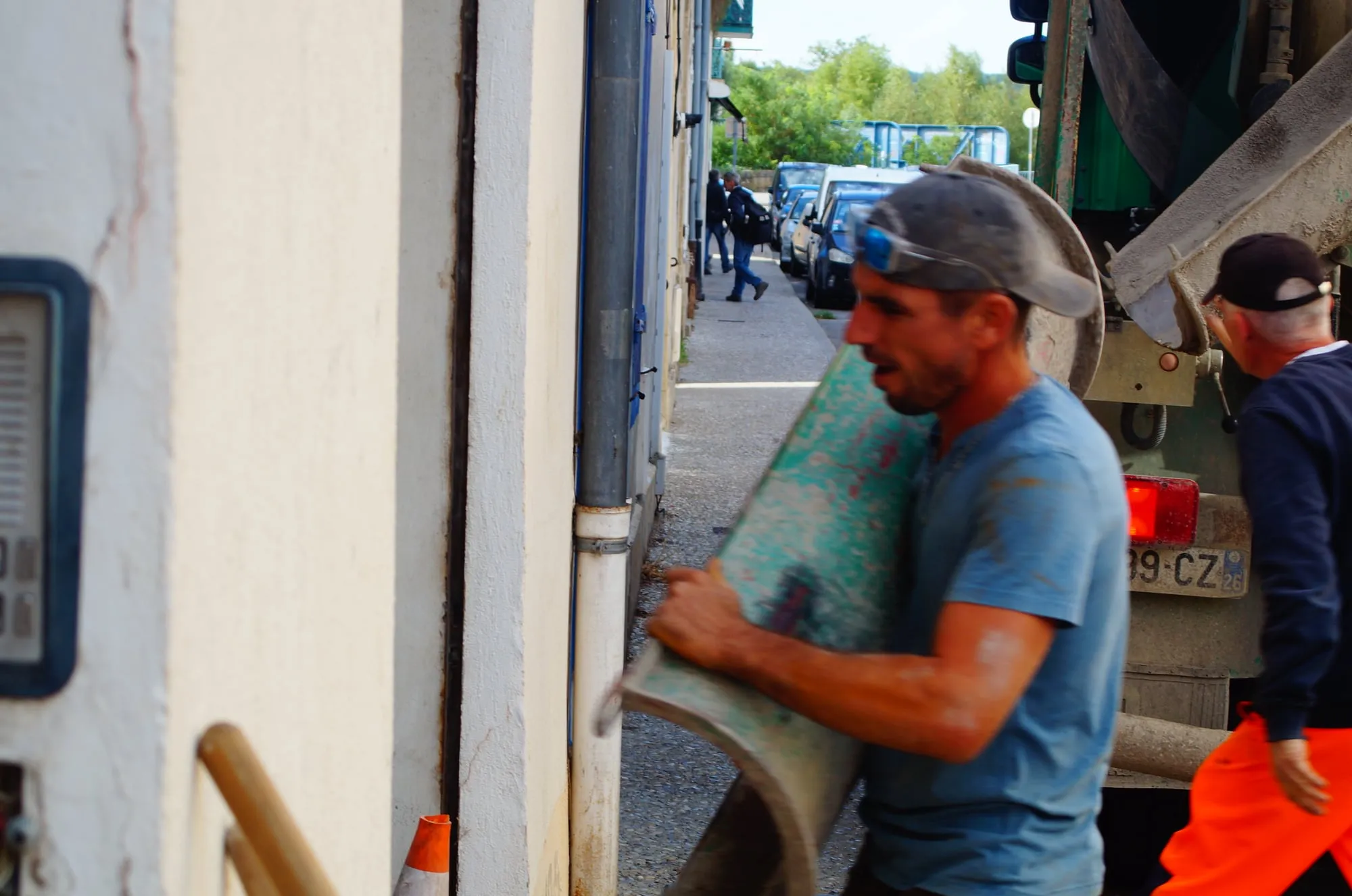 Maçon portant une goulotte devant le camion toupie