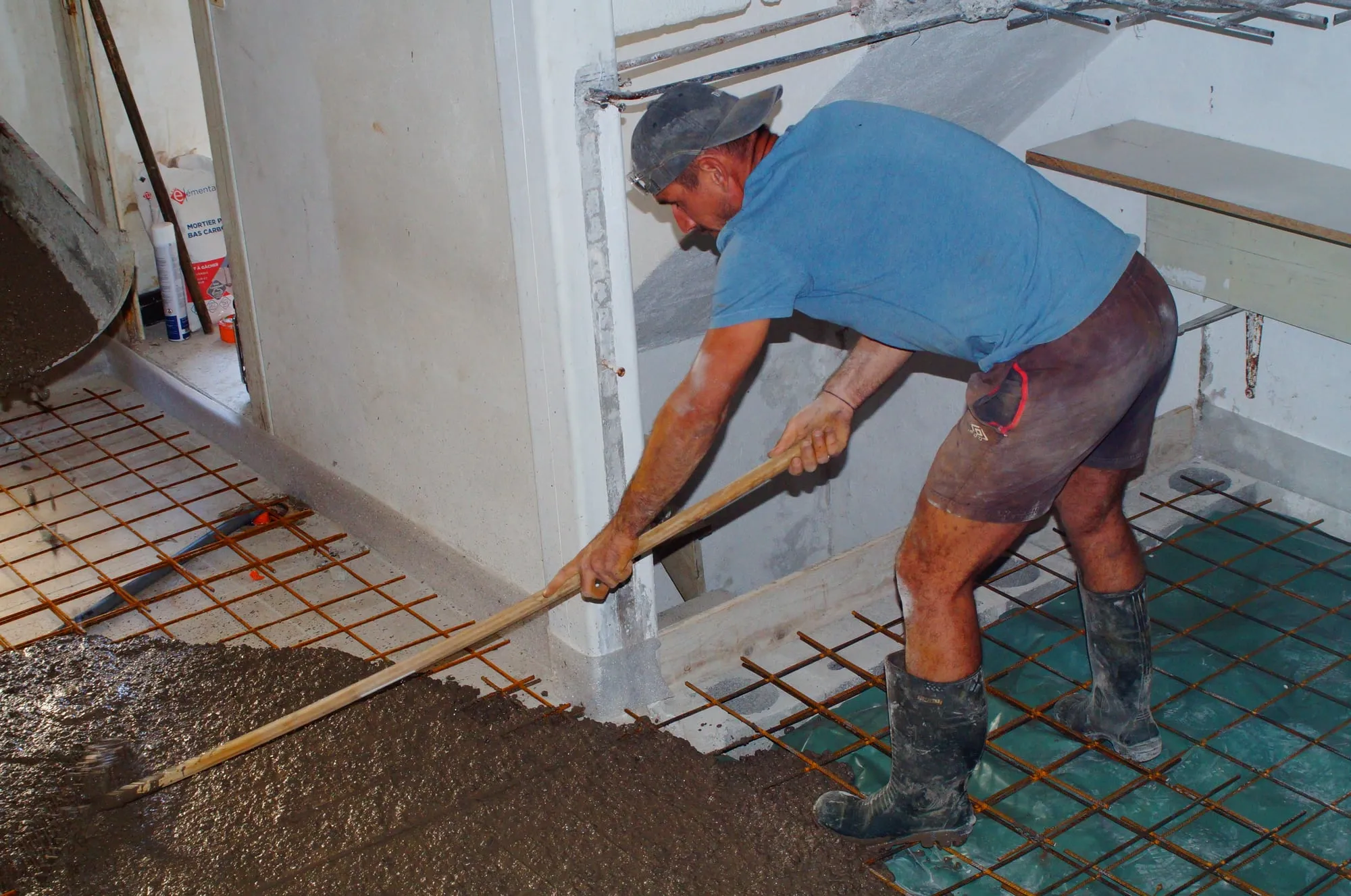 Maçon penché étalant le béton frais