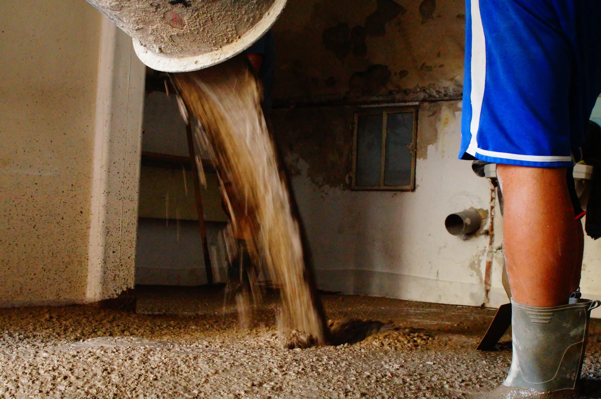 Béton sortant de la goulotte au pied du maçon