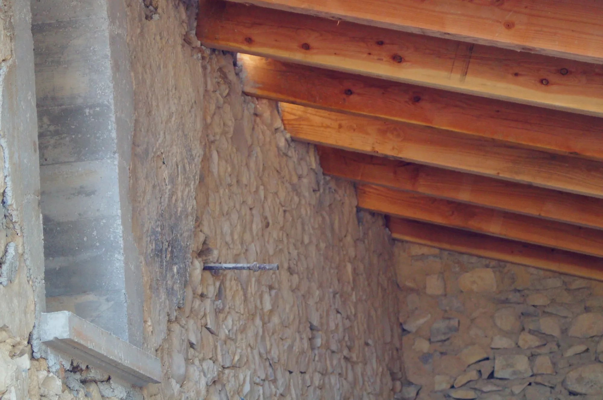 Chevrons de la charpente scellés dans le mur en pierre