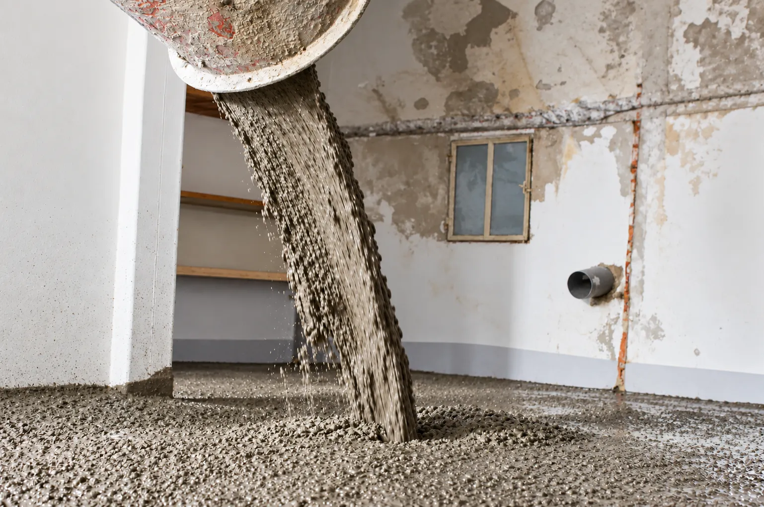 Béton déversé d'une bétonnière dans une pièce en rénovation