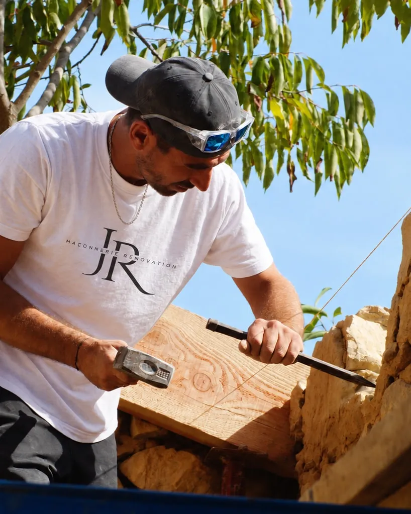 Jérémy Rochas, gérant de JR Maçonnerie Rénovation, taillant une pierre au burin sur un mur