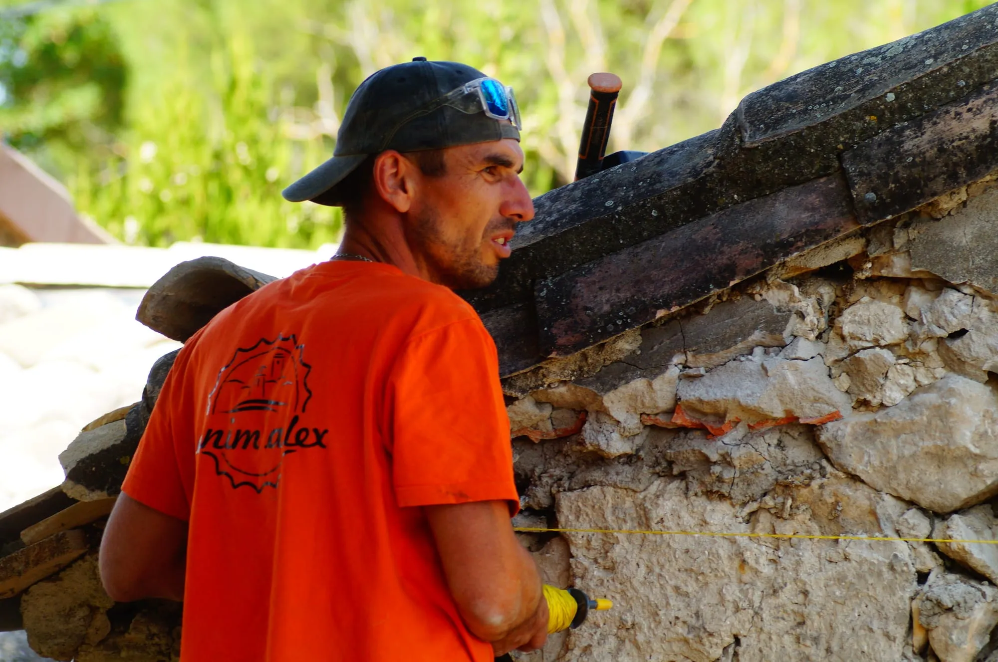 Maçon de dos travaillant sous l’avant-toit d’un mur ancien