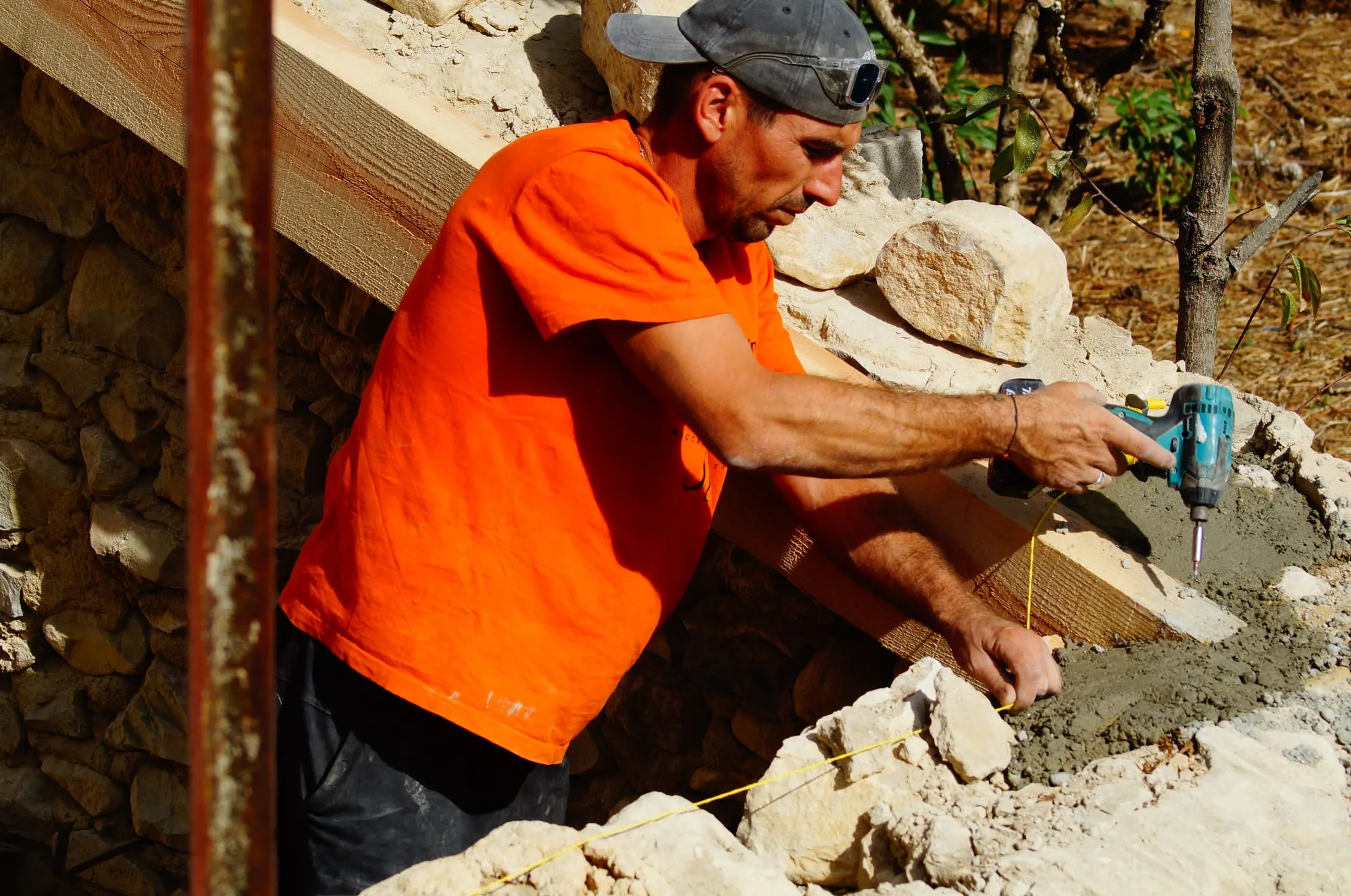 Maçon garnissant de mortier le dessus d’un mur en pierre