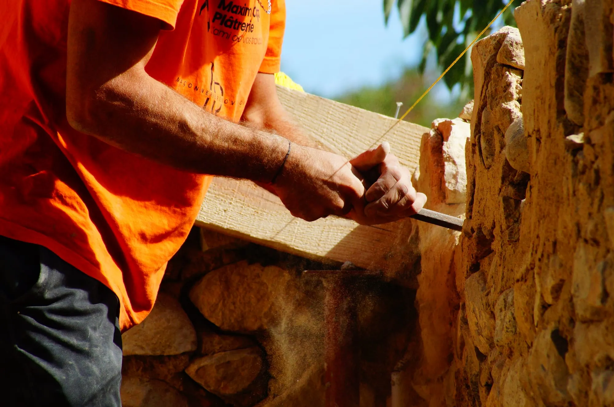 Maçon réglant l’alignement de la poutre le long du mur