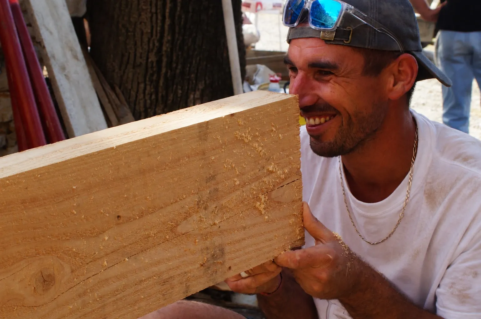 Maçon souriant tenant une poutre en bois avant la pose